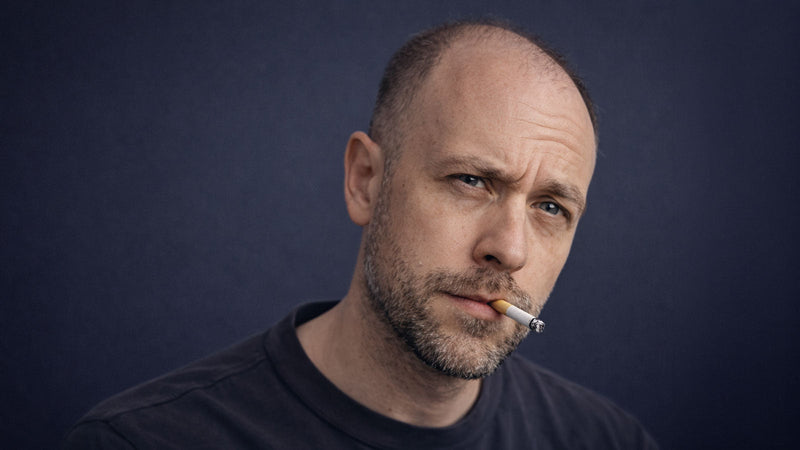 bald man smoking cigarette illustrating link between smoking and hair loss