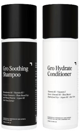 Two bottles of hair care products from Gro Clinics. The left bottle, part of the "Soothing Shampoo & Hydrate Conditioner Duo," labeled "Soothing Shampoo," boasts ingredients such as watermelon oil and coconut cleansers for healthy hair. The right bottle, labeled "Hydrate Conditioner," features vitamin E and shea butter. Both bottles have black caps.